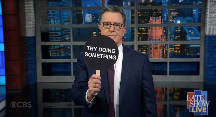 Screenshot from The Late Show Live with Stephen Colbert, March 4, 2025. The host, Colbert, is holding a Try Doing Something paddle in the show following President Trump's speech to Congress.