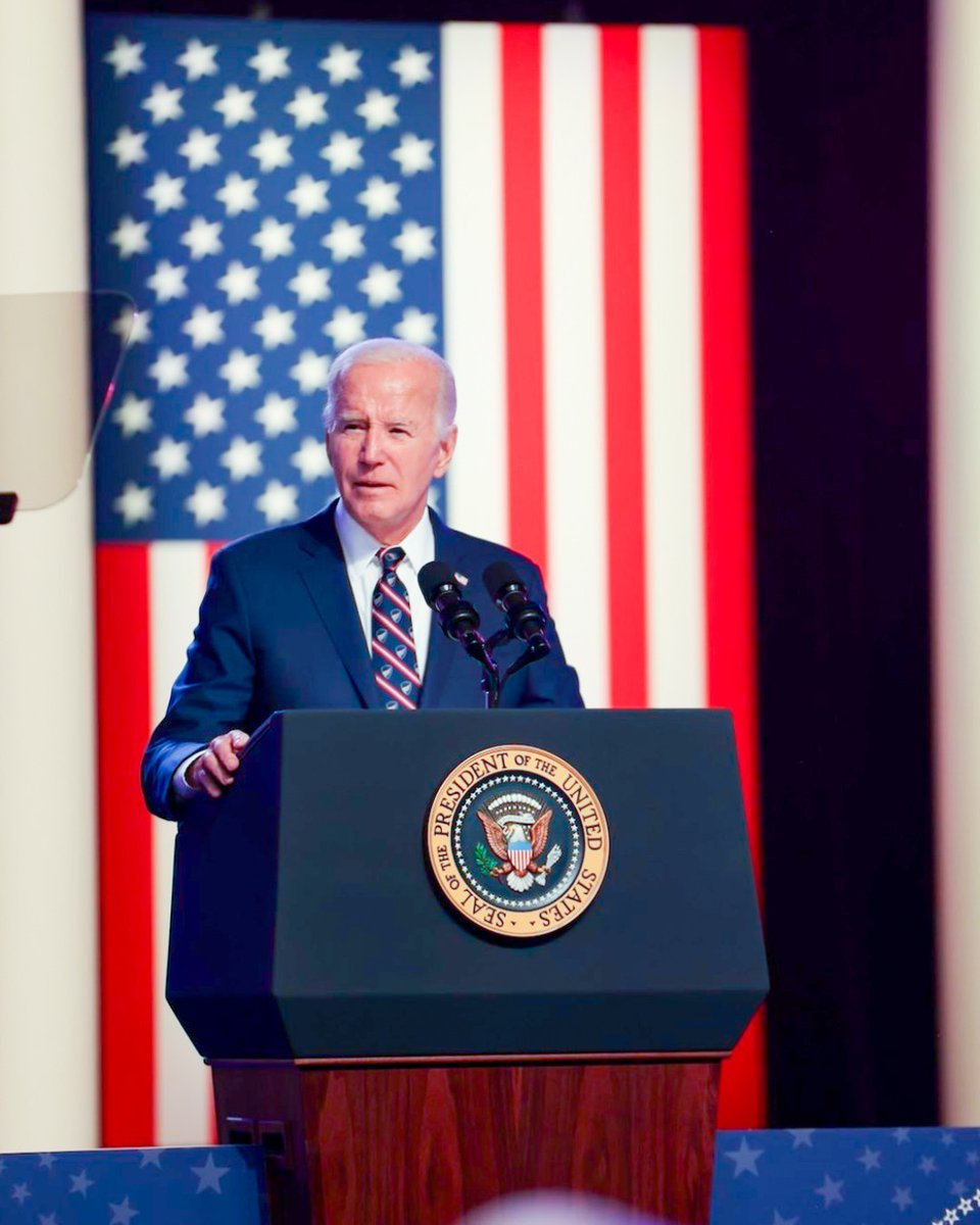 President Joe Biden delivers remarks at a podium to supporters while standing in front of an American flag. 
