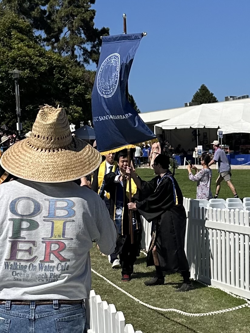 Arik Cheslog hands off the UC Santa Barbara banner during the commencement procession for the Class of 2024.