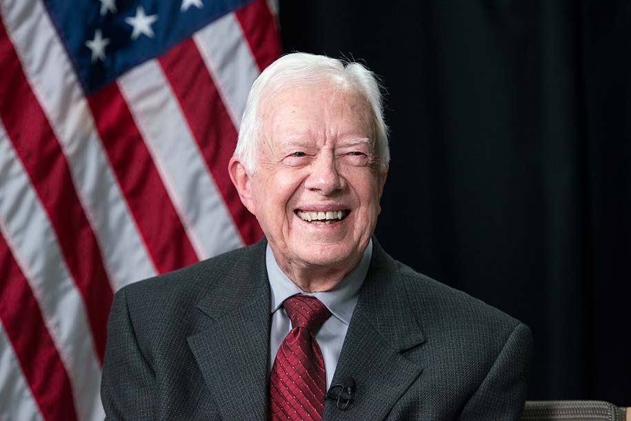 A photo of former President Jimmy Carter in front of an American flag.
